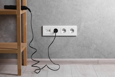 Photo of Power sockets and electric plug on grey wall