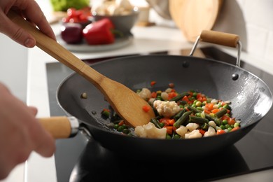 Photo of Man stirring mix of fresh vegetables in frying pan, closeup