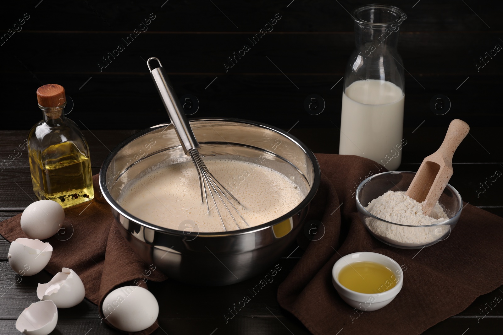 Photo of Composition with whisk and dough in bowl on wooden table