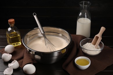 Photo of Composition with whisk and dough in bowl on wooden table