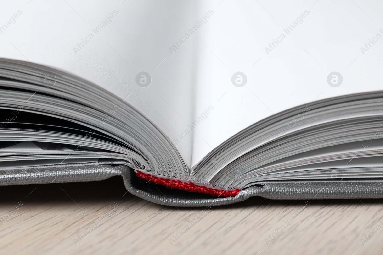 Photo of Open book with hard cover on wooden table, closeup