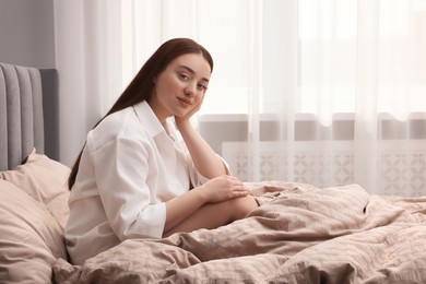 Photo of Beautiful woman sitting on bed at home, space for text. Lazy morning