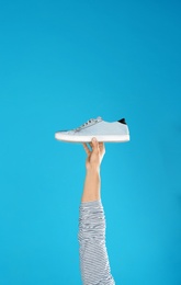 Photo of Young man holding comfortable shoe on light blue background, closeup