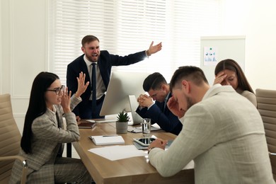Photo of Boss screaming at employees on meeting in office. Toxic work environment