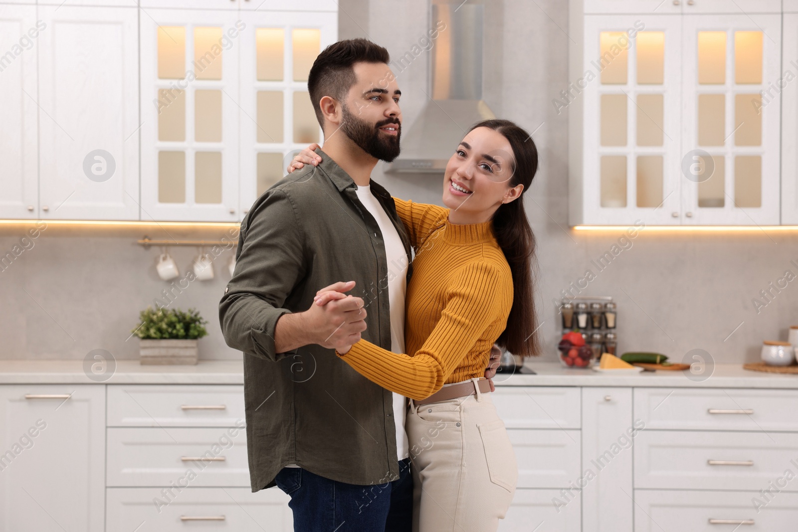 Photo of Happy lovely couple dancing together in kitchen