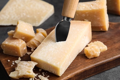 Photo of Parmesan cheese with knife on grey table, closeup