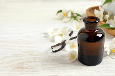 Photo of Jasmine essential oil and fresh flowers on white wooden table, space for text