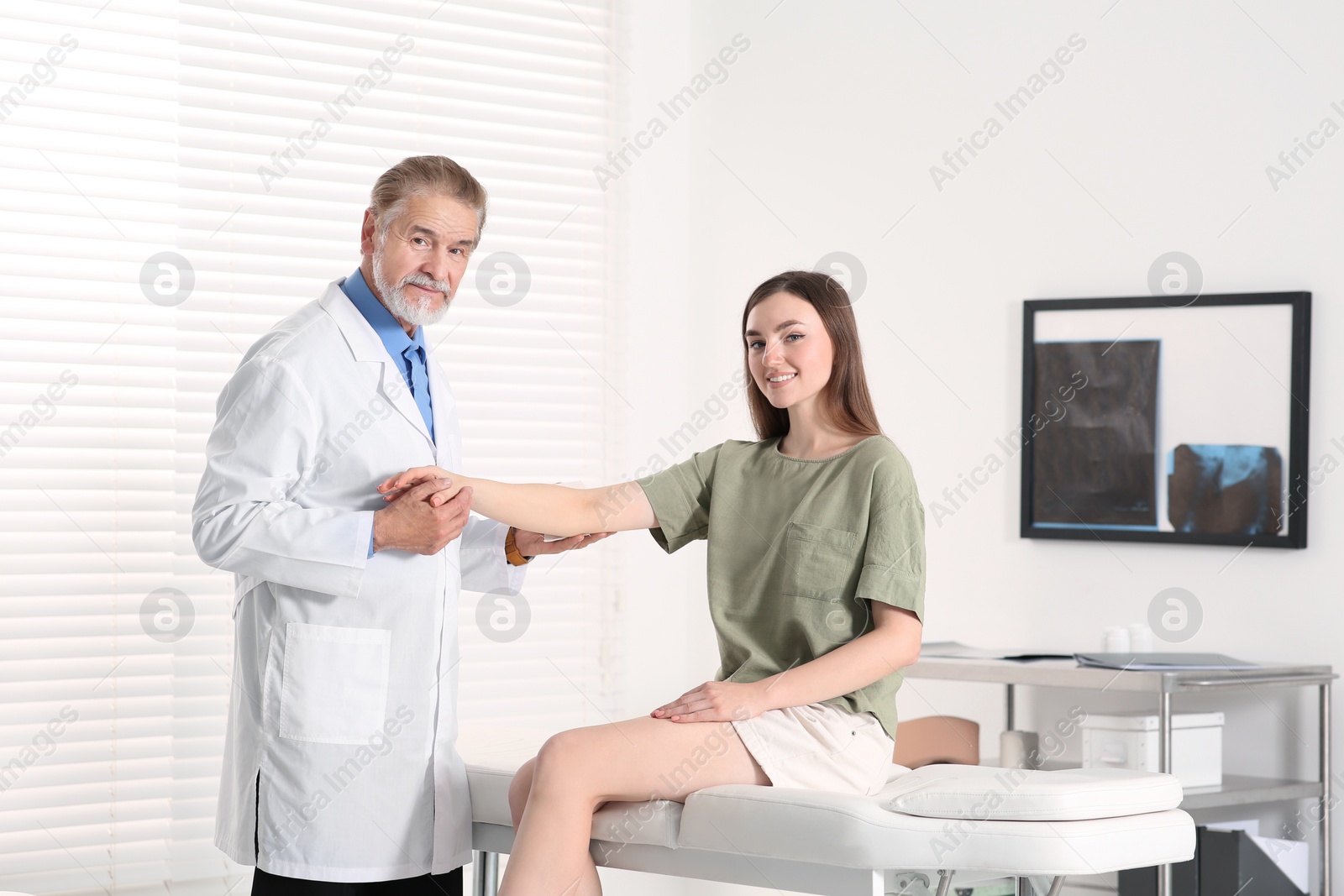 Photo of Orthopedist examining patient with injured arm in clinic