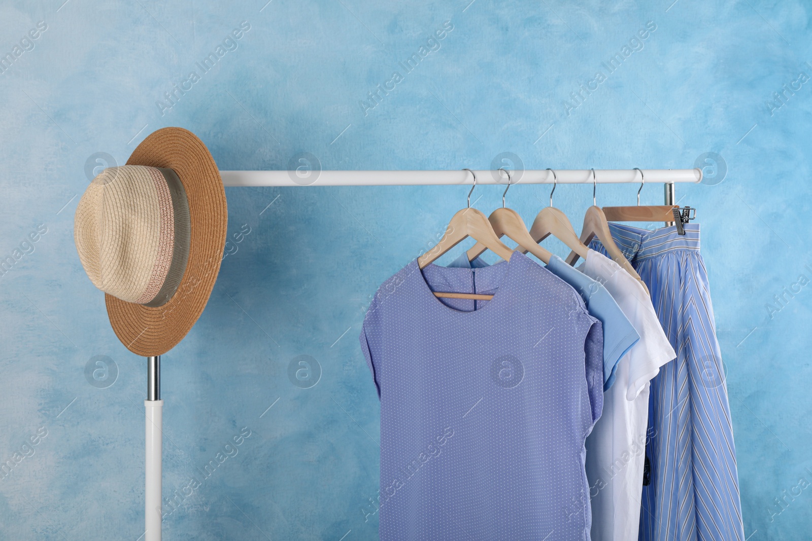 Photo of Rack with stylish clothes near light blue wall indoors