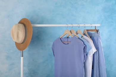 Rack with stylish clothes near light blue wall indoors