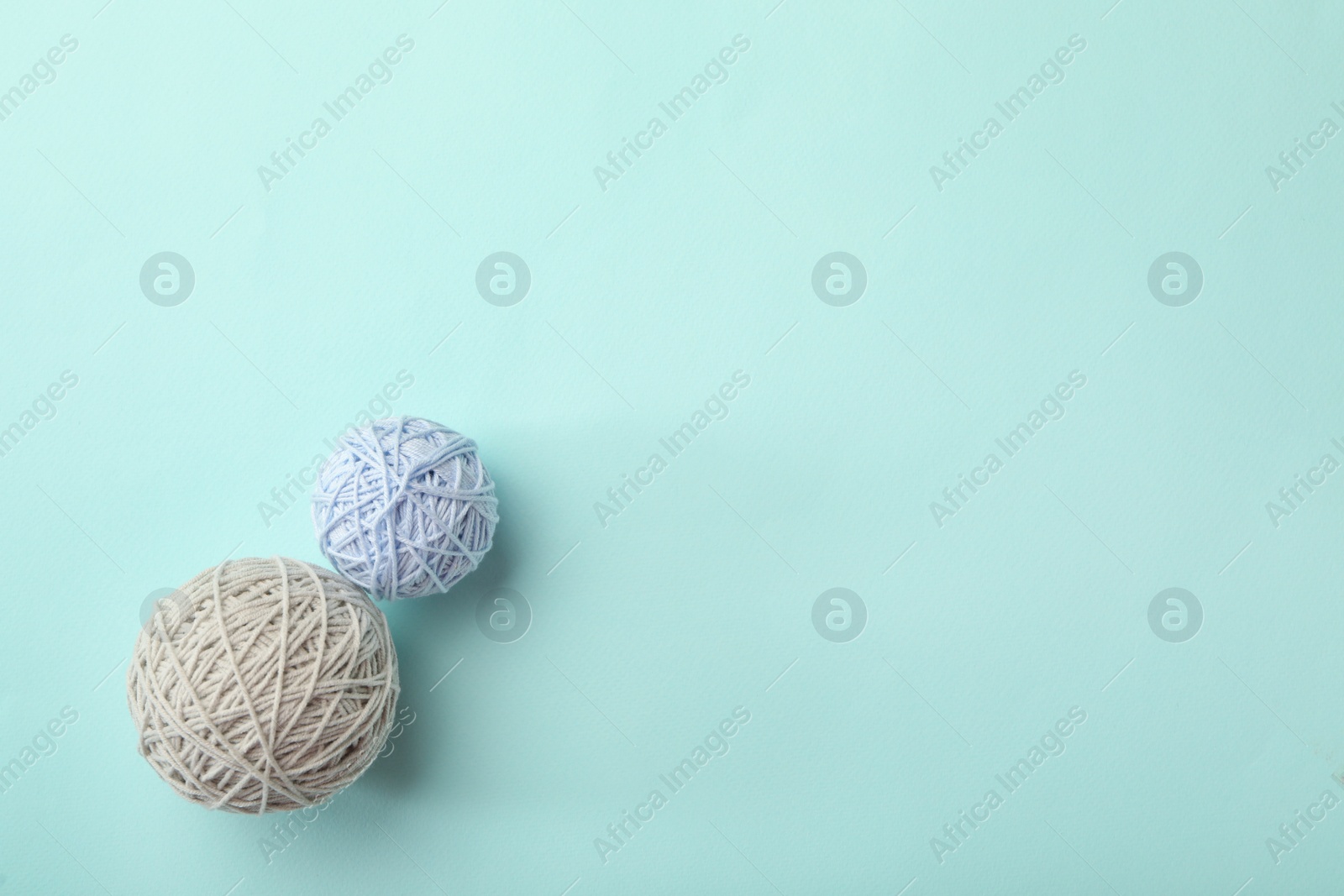 Photo of Soft colorful woolen yarns on light blue background, flat lay. Space for text