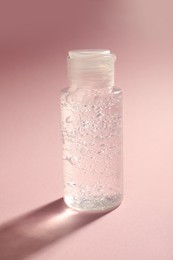 Bottle of cosmetic gel on pale pink background