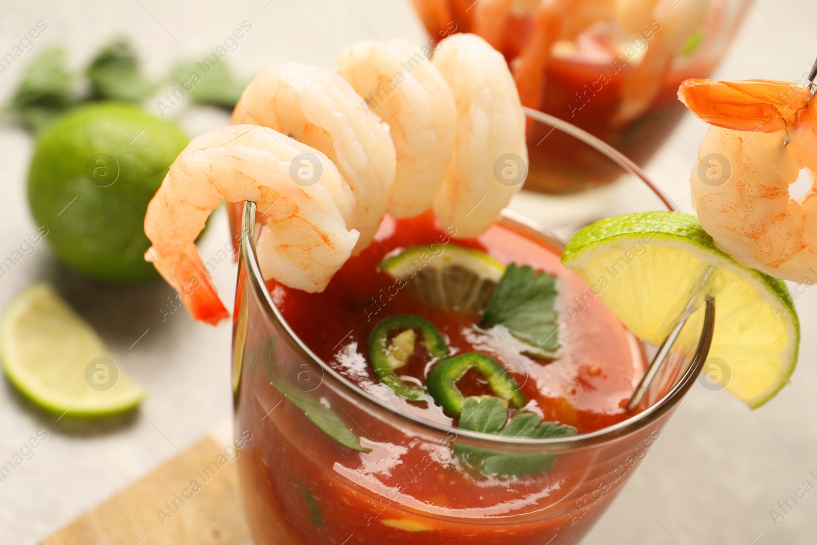 Photo of Tasty shrimp cocktail with sauce in glass and lime on light table, closeup