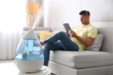 Photo of Modern air humidifier and blurred man on background