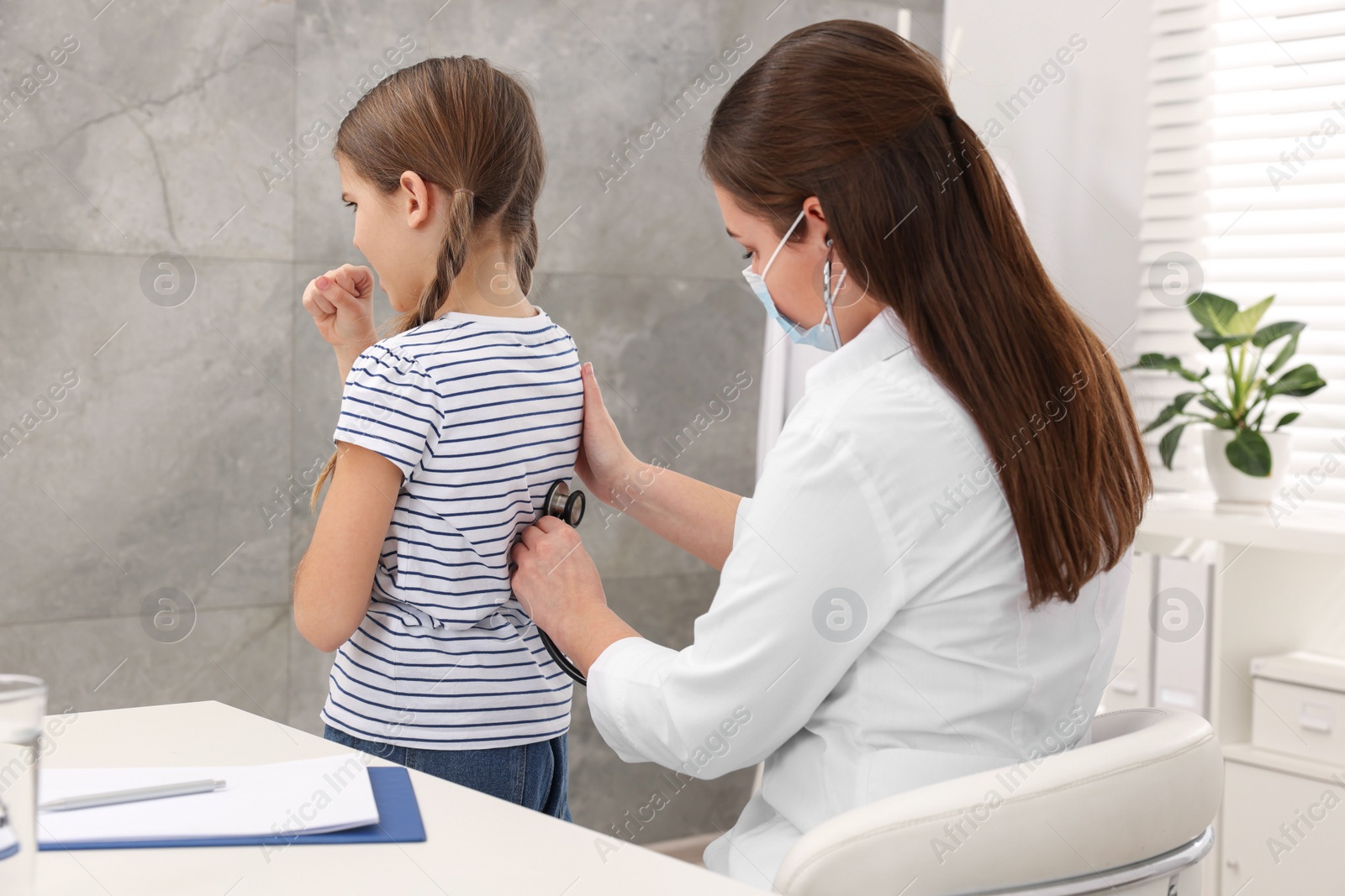 Photo of Doctor examining coughing girl in hospital. Cold symptoms