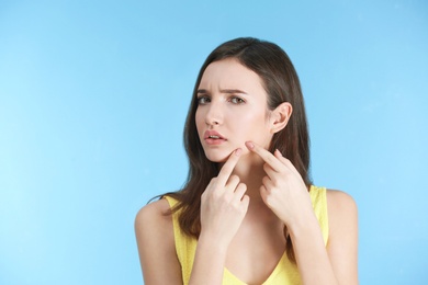 Teenage girl with acne problem against color background