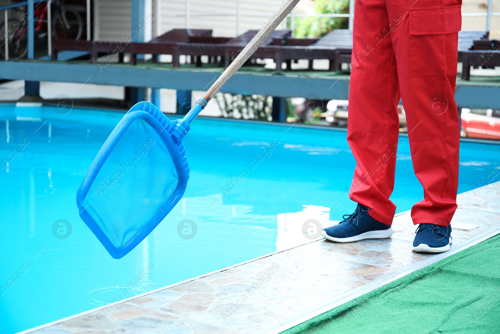 Photo of Male worker cleaning outdoor pool with scoop net