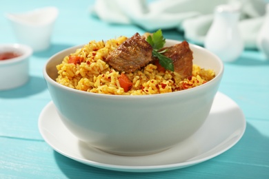 Photo of Bowl of tasty rice pilaf with meat on table