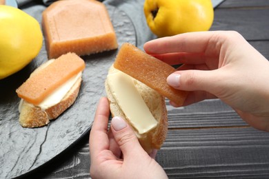 Photo of Woman making sandwich with quince paste at black wooden table, closeup