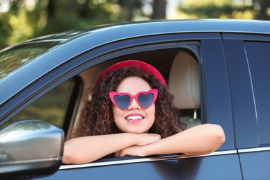 Photo of Young beautiful African-American woman wearing heart shaped glasses in car