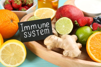 Photo of Card with phrase Immune System and fresh products on table, closeup