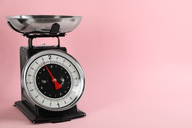 Photo of Retro mechanical kitchen scale on pink background, space for text