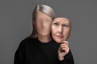 Faceless woman holding her face mask showing emotion on grey background. Personality crisis.