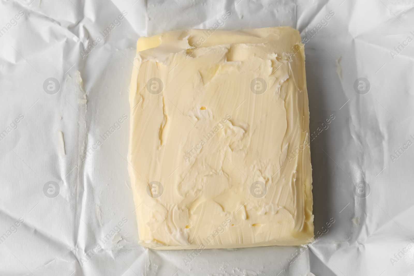 Photo of Piece of tasty homemade butter on paper wrap, top view