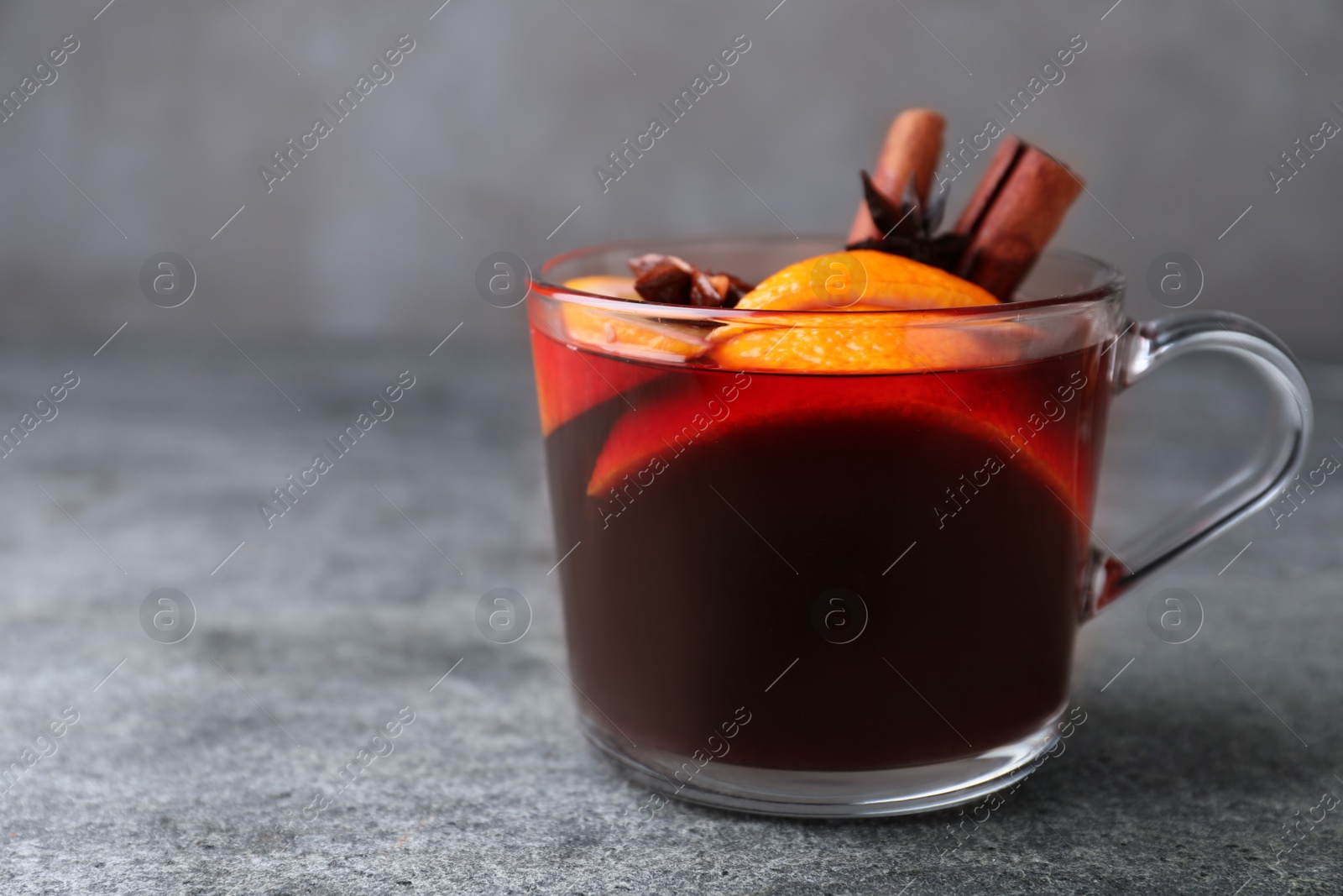 Photo of Aromatic mulled wine on grey table, closeup