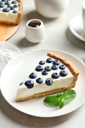 Plate with piece of tasty blueberry cake on gray table