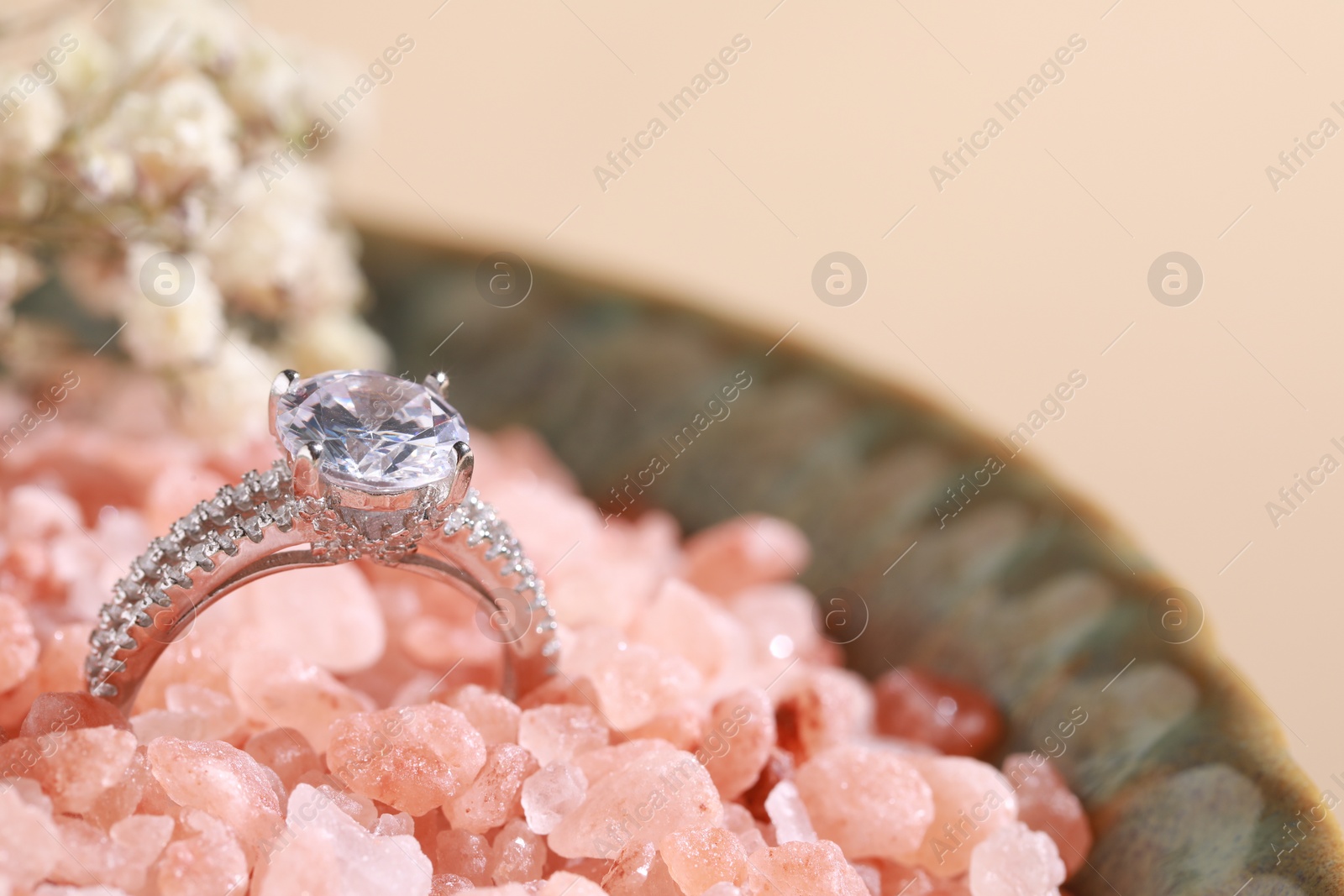 Photo of Luxury jewelry. Stylish presentation of elegant ring on sea salt, closeup. Space for text