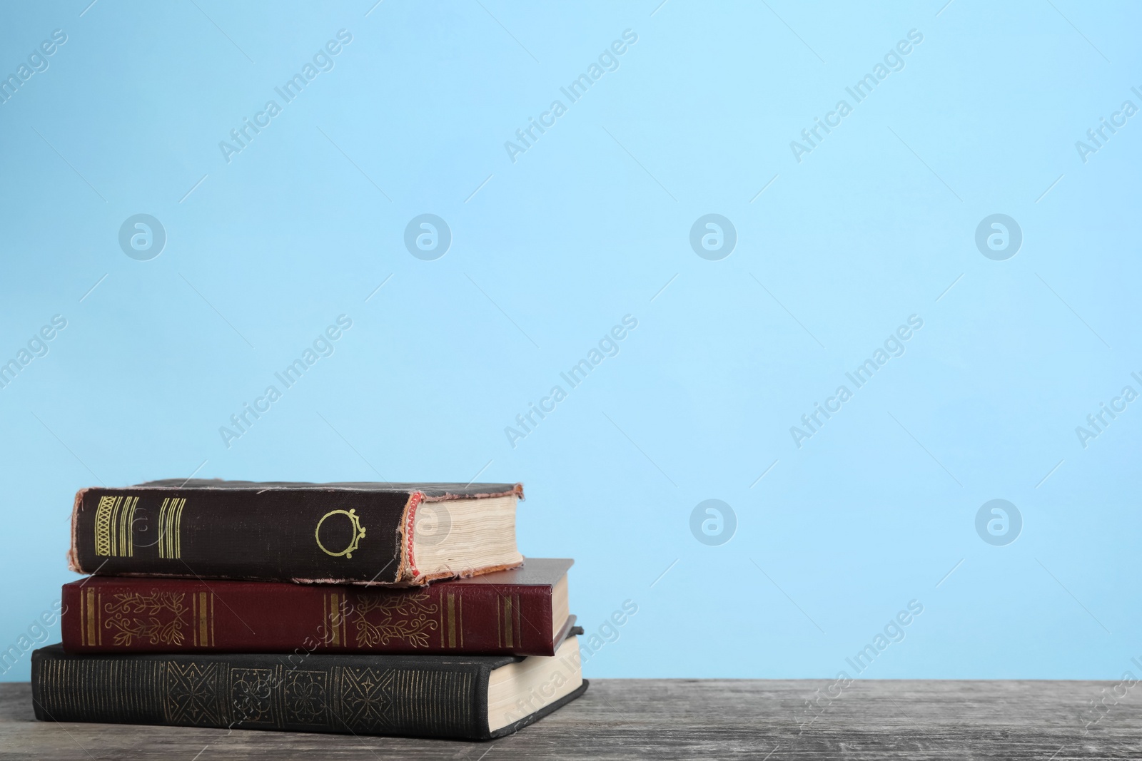 Photo of Stack of old books on wooden table, space for text