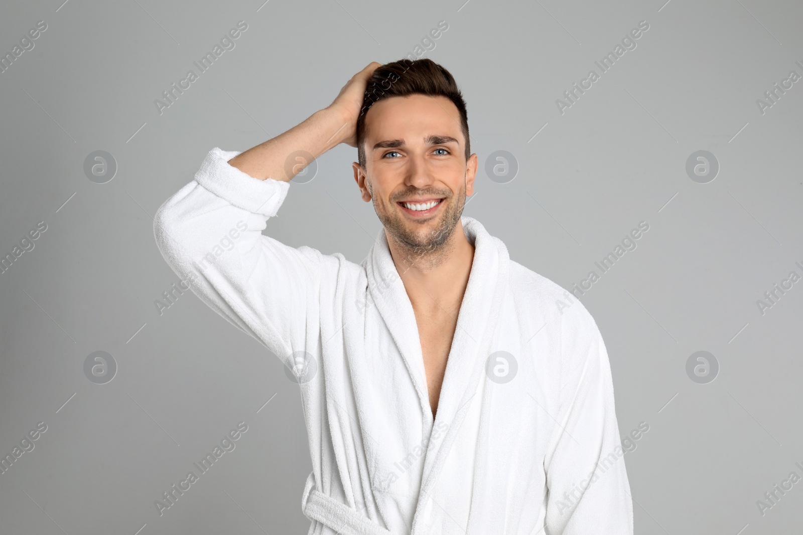 Photo of Happy young man in bathrobe on light grey background