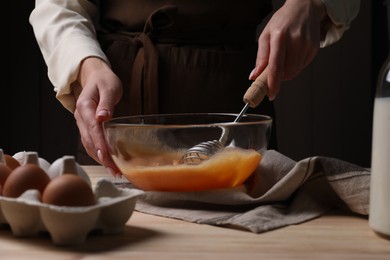 Photo of Woman whisking eggs in bowl at table, closeup