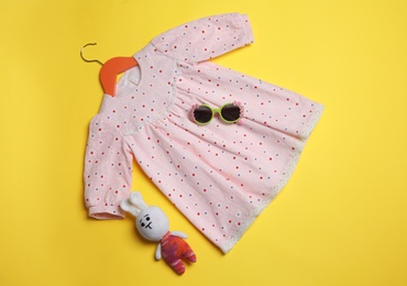 Photo of Flat lay composition with baby dress and accessories on yellow background