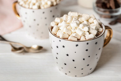 Photo of Delicious cocoa drink with marshmallows in cup on white wooden table, space for text