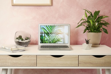 Houseplants and laptop on table in office interior