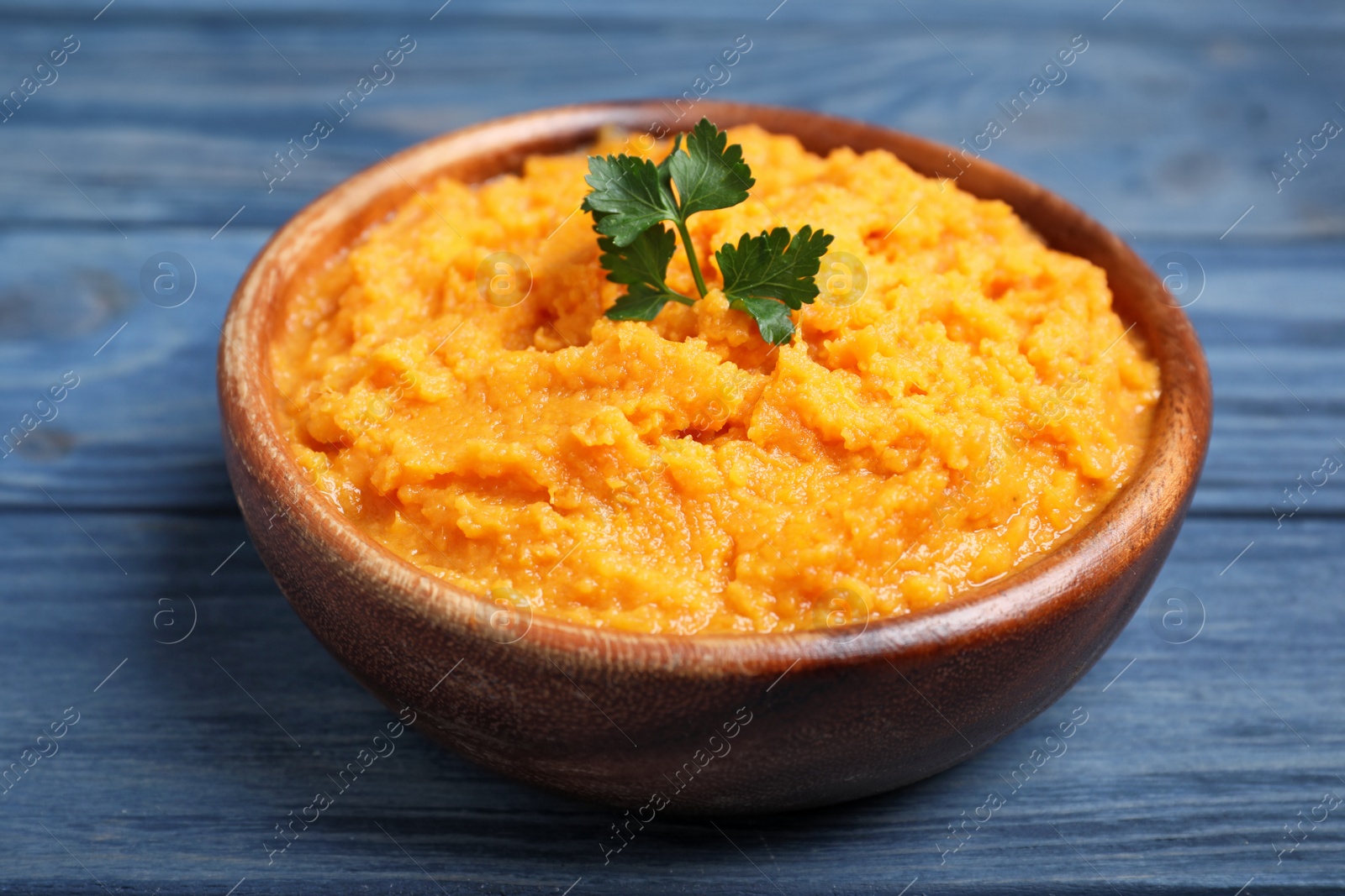 Photo of Bowl with mashed sweet potatoes on wooden background