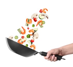 Image of Man tossing ingredients in wok on white background, closeup