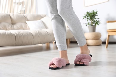 Photo of Woman wearing soft slippers at home, closeup of legs