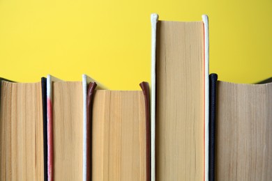 Collection of hardcover books on yellow background, closeup