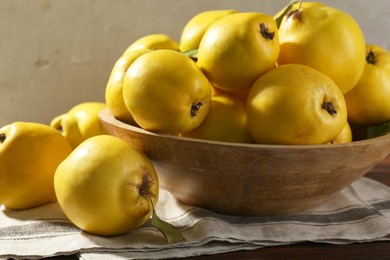 Photo of Tasty ripe quince fruits in bowl on wooden table, closeup