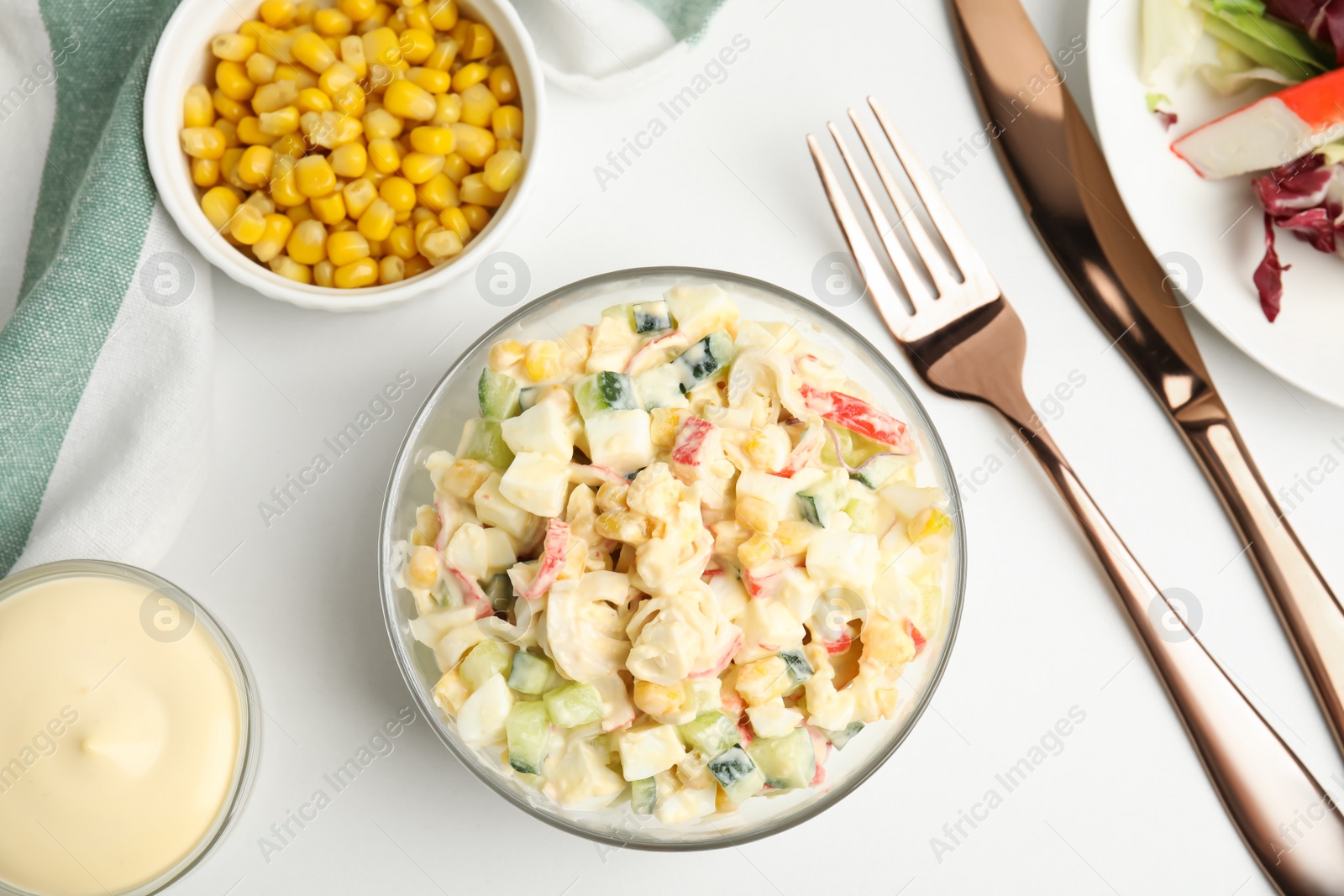 Photo of Delicious salad with fresh crab sticks and corn served on white table, flat lay