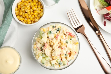 Delicious salad with fresh crab sticks and corn served on white table, flat lay
