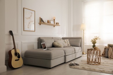 Photo of Living room with comfortable grey sofa and stylish interior elements near window