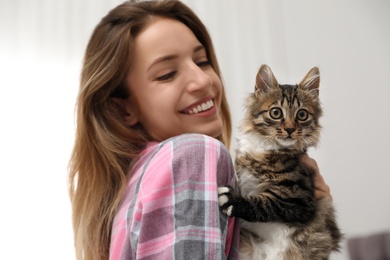 Photo of Woman wearing pajama with cat at home. Owner and pet