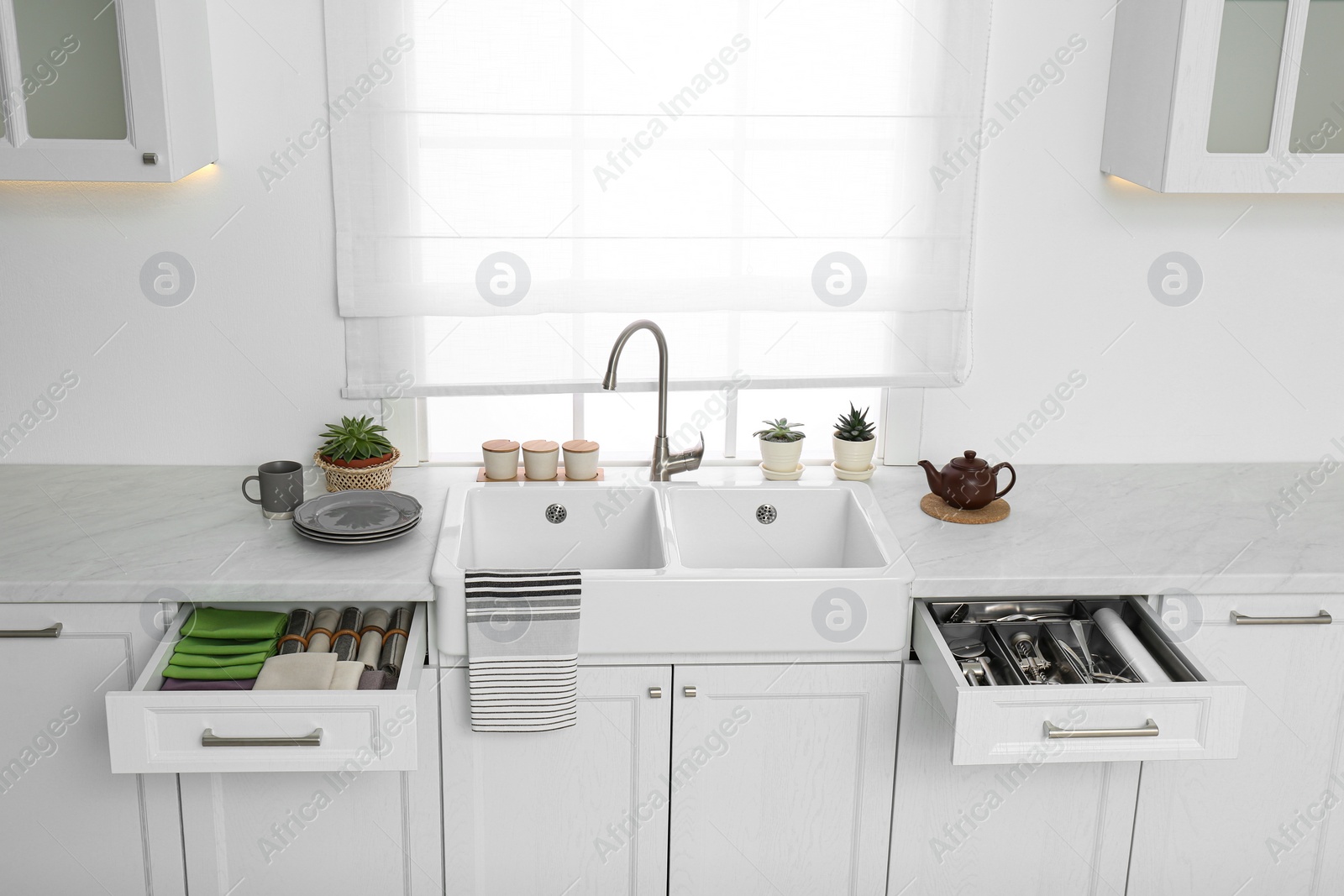 Photo of Open drawers with different utensils, towels and napkins in kitchen