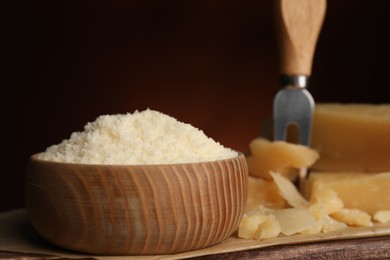 Photo of Delicious grated parmesan cheese in bowl on wooden table