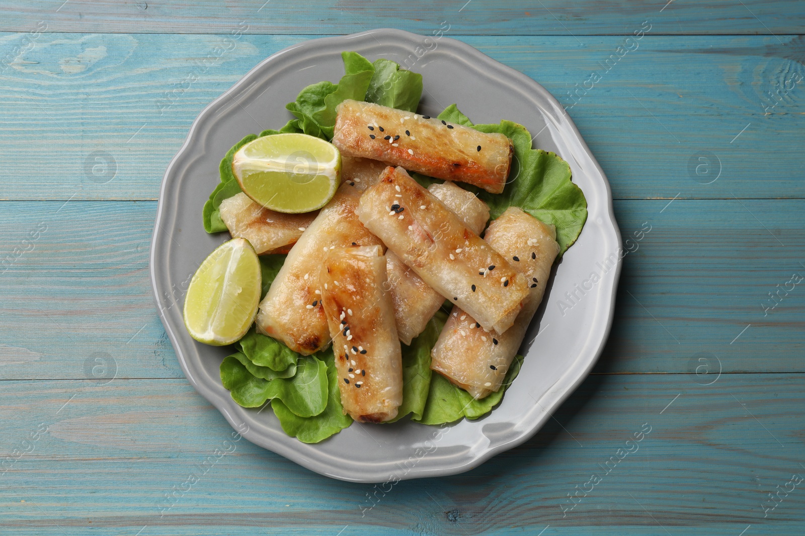 Photo of Tasty fried spring rolls on light blue wooden table, top view