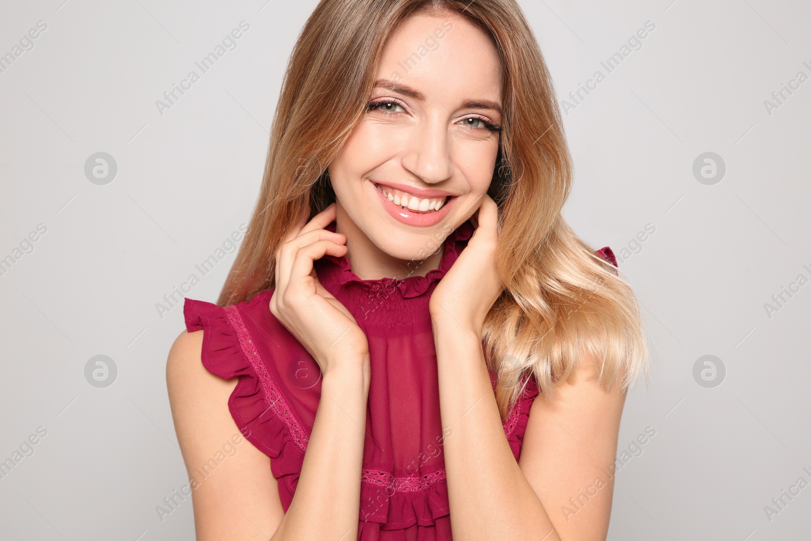 Photo of Portrait of beautiful smiling woman in stylish clothes on light background